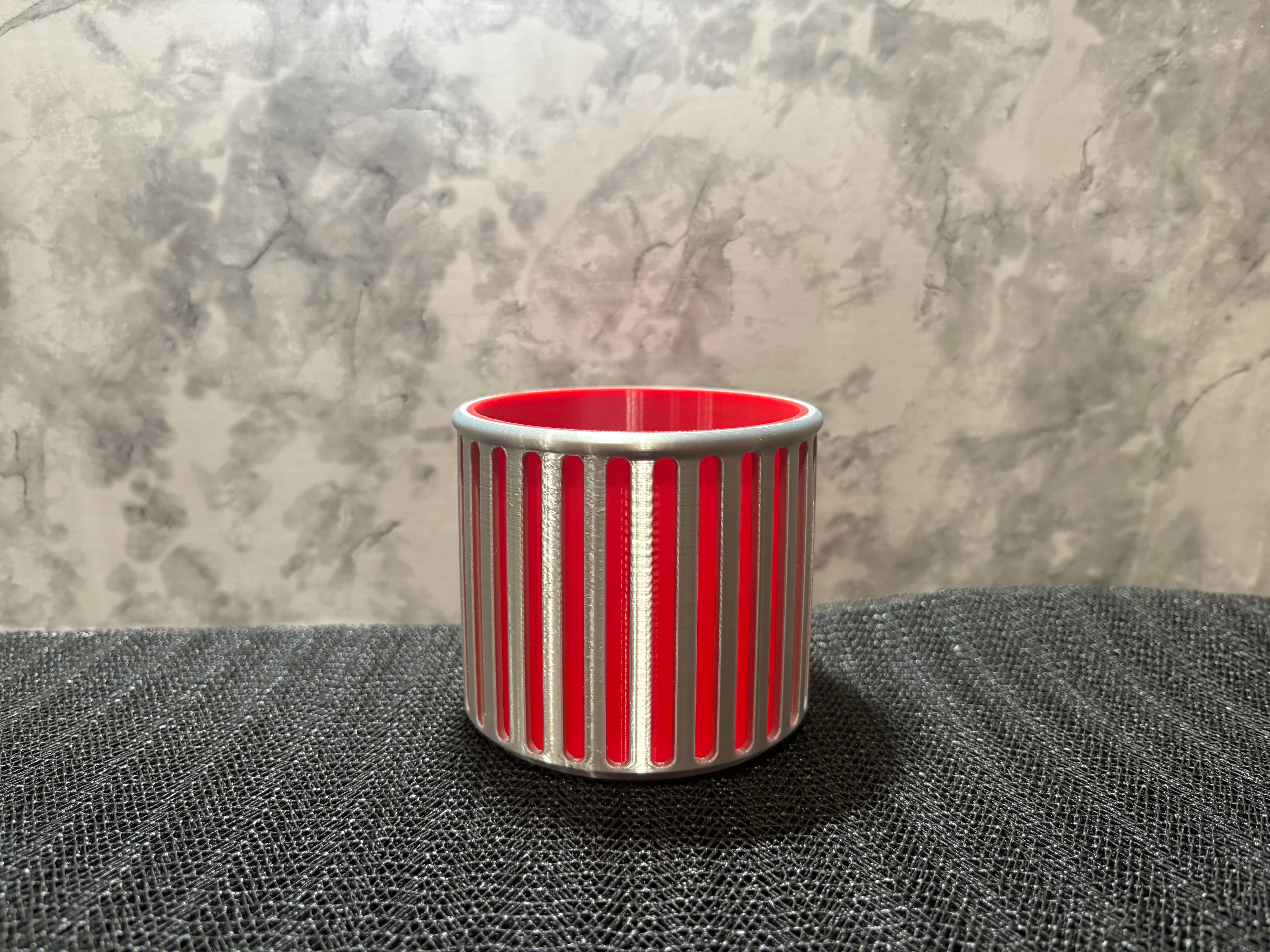 Silver and red 3D printed modern ribbed cylindrical pencil holder on a desk